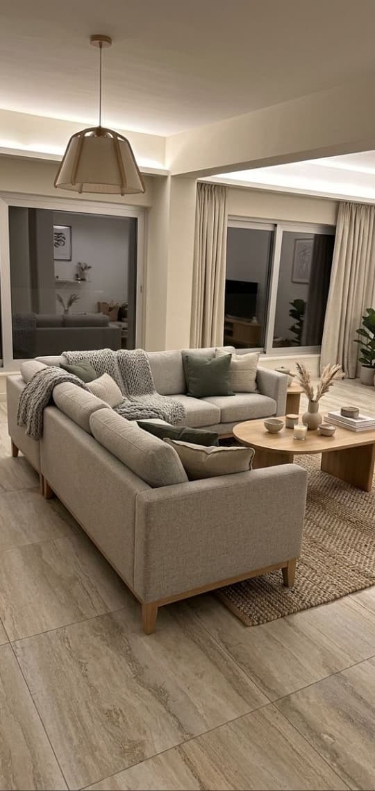 The styled room — warm light, sage cushions, wood coffee table, jute rug